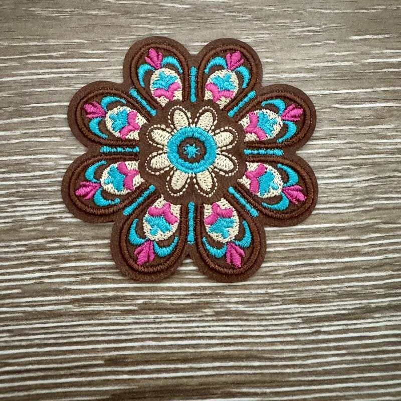 Boho mandala flower iron-on patch stitched in pink, teal and cream on warm brown petals