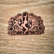 Cow print saguaro cactus desert engraved leather-look iron-on patch with mesas, rising sun and wildflowers by On A Whim Hats