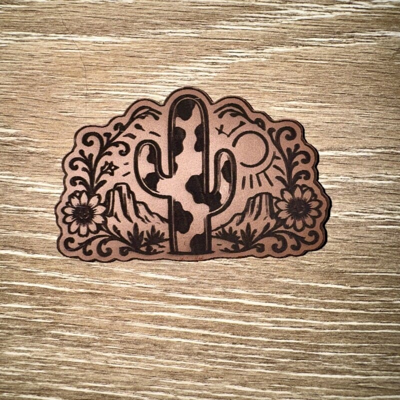 Cow print saguaro cactus desert engraved leather-look iron-on patch with mesas, rising sun and wildflowers by On A Whim Hats