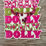 Dolly Country Icon iron-on patch with a floral cattle skull over repeated pink and green lettering by On A Whim Hats