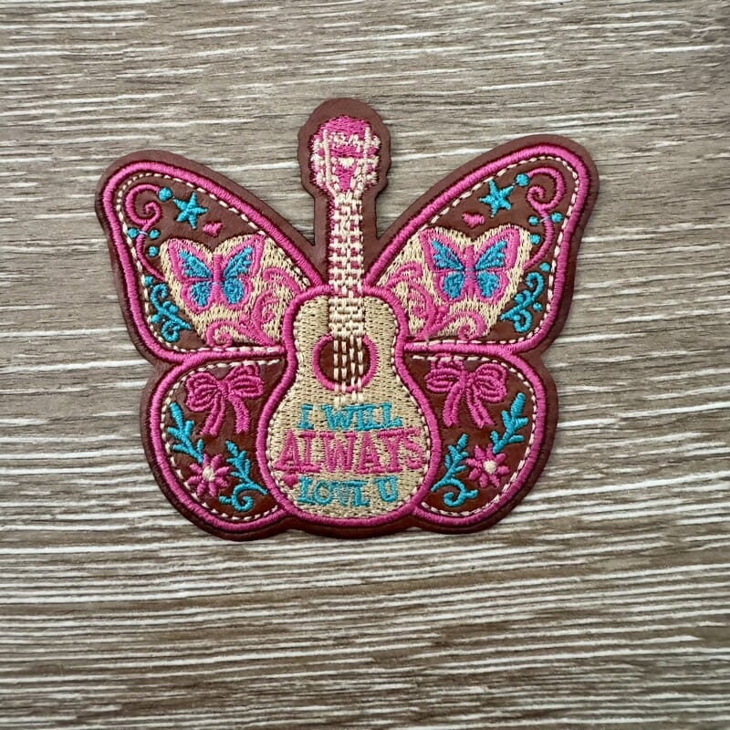 Dolly guitar butterfly love song iron-on patch embroidered in pink, teal and brown with floral and bow details