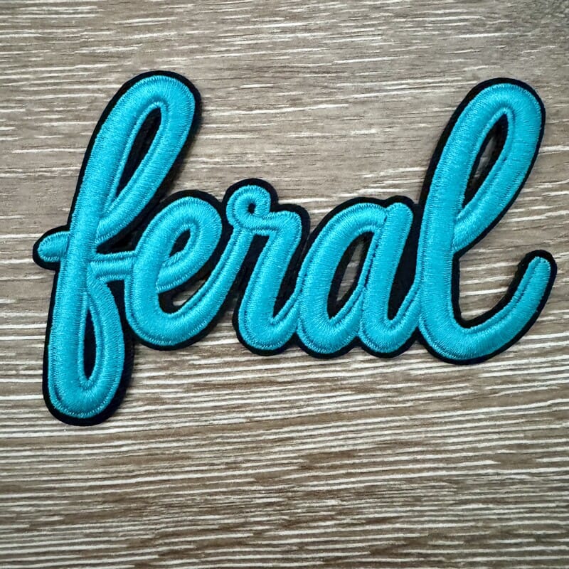 Feral script iron-on patch in teal with black outline stitching for trucker hats and jackets by On A Whim Hats