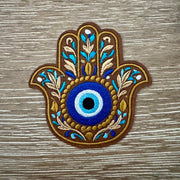 Hamsa hand evil eye boho iron-on patch in brown and gold with floral design and blue eye center by On A Whim Hats