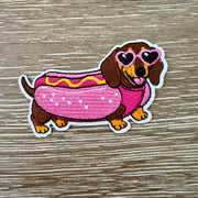 Hot Dog Doxie iron-on patch of a dachshund in a pink bun costume with mustard and heart sunglasses by On A Whim Hats