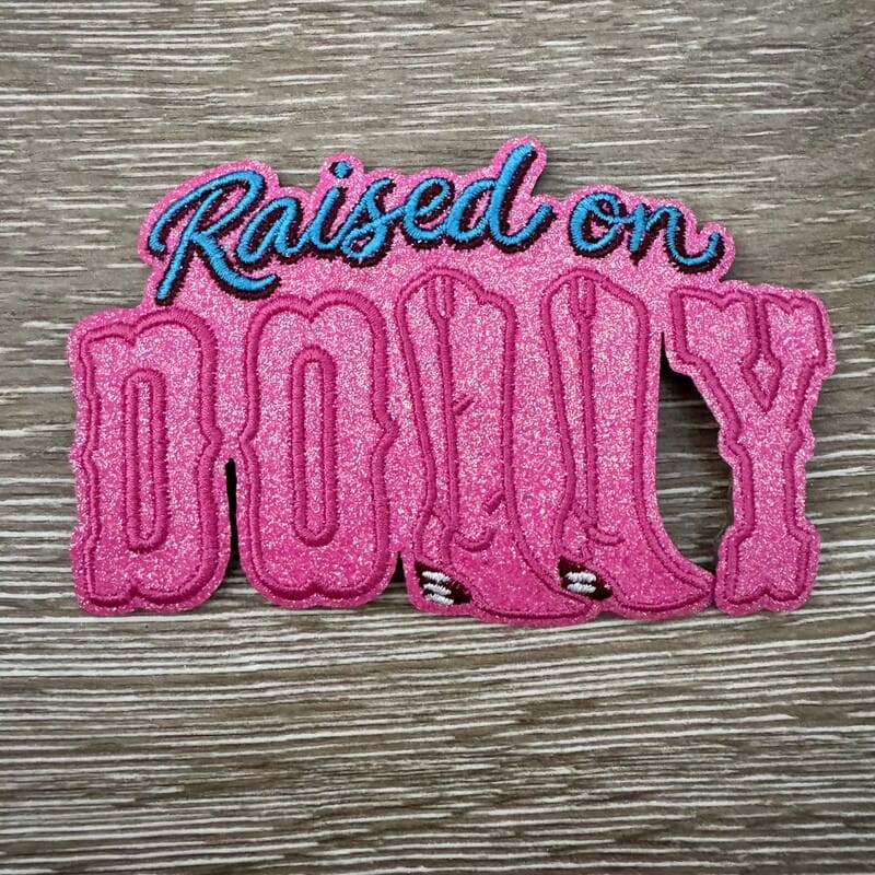Raised on Dolly Music glitter iron-on patch with block lettering and cowgirl boot details for hats by On A Whim Hats