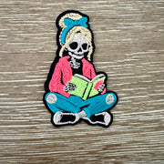 On A Whim Hats Skeleton Girl Reading Iron-On Patch