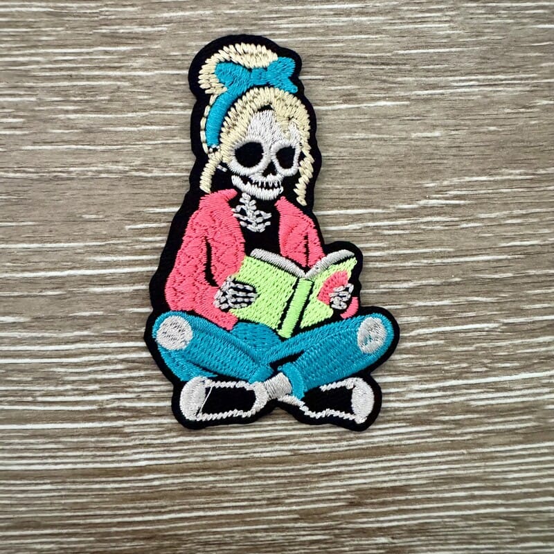 On A Whim Hats Skeleton Girl Reading Iron-On Patch