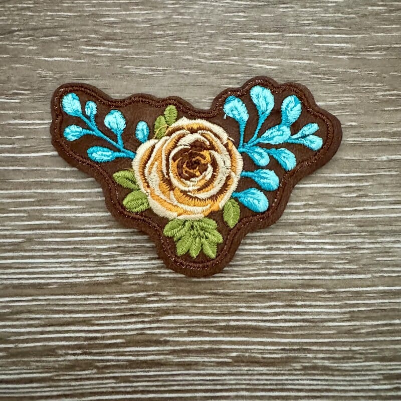Golden Rose iron-on patch with yellow rose and turquoise leaves on brown western background