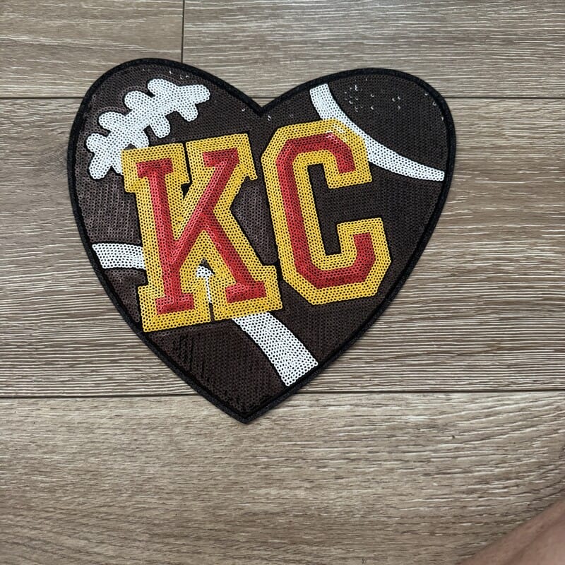 Heart-shaped KC football sequin iron-on patch with red and gold KC letters for game-day hats by On A Whim Hats