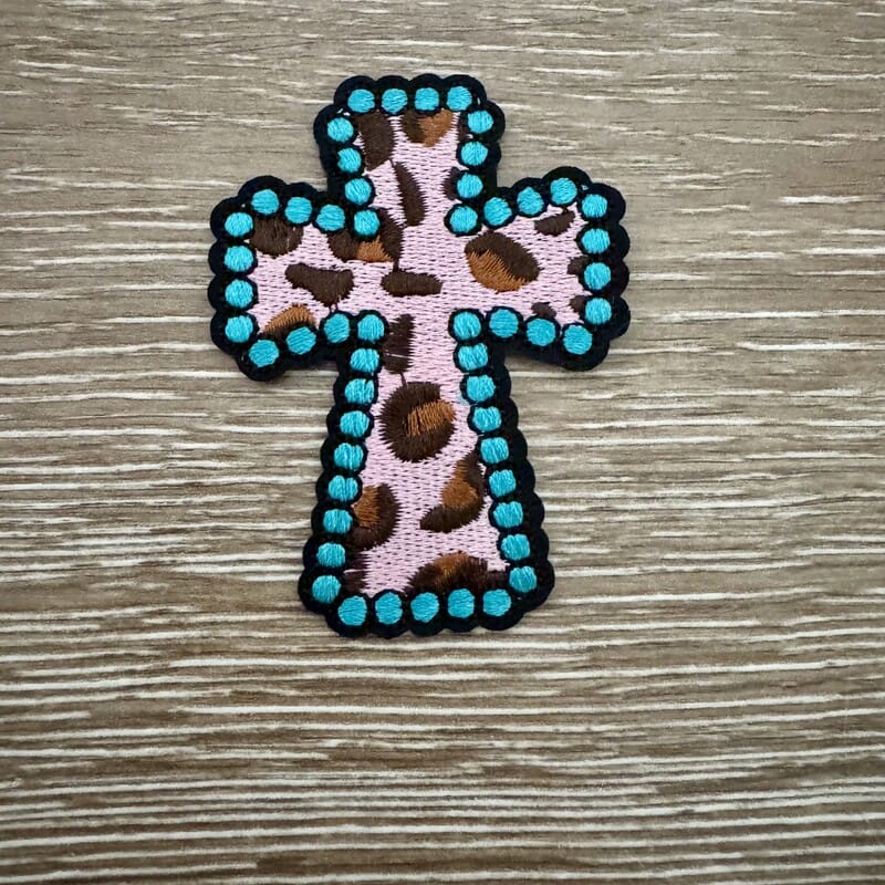 Leopard Cross iron-on patch with pink leopard print cross edged in turquoise studs on black