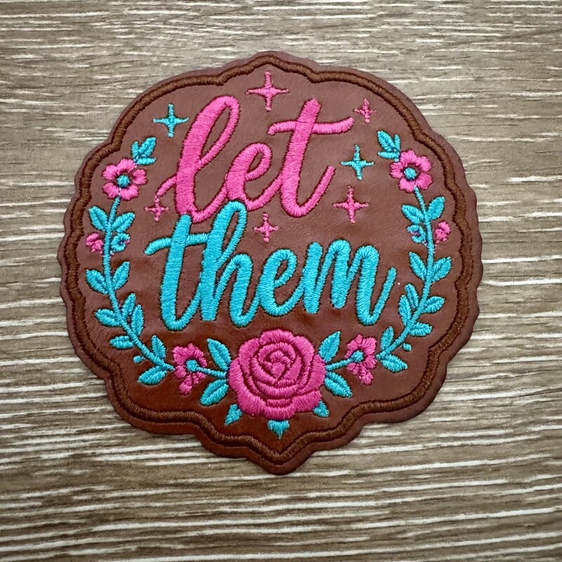 Let Them floral leather iron-on patch with pink script, rose wreath and turquoise leaves on brown