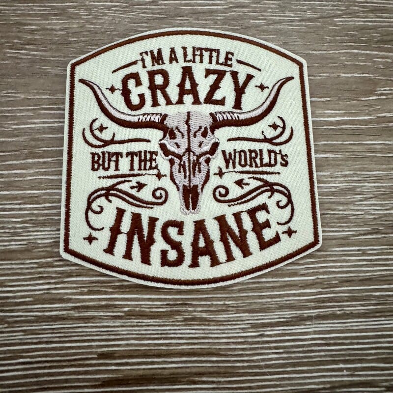 Little Crazy World's Insane western iron-on patch with steer skull and brown lettering on cream