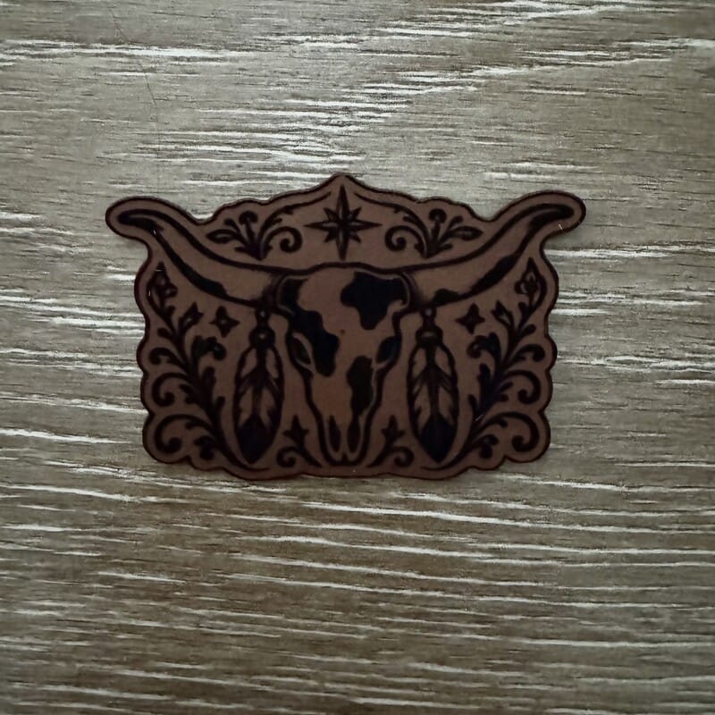 Longhorn steer skull and feathers laser-engraved leather-look iron-on patch with north star and floral scrollwork