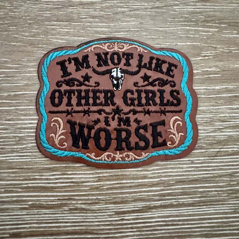 Not Like Other Girls leather iron-on patch with cream western lettering and steer skull on brown