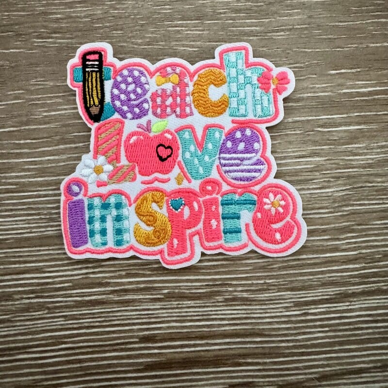 Teach Love Inspire embroidered iron-on patch with patterned letters, pencil, apple and heart