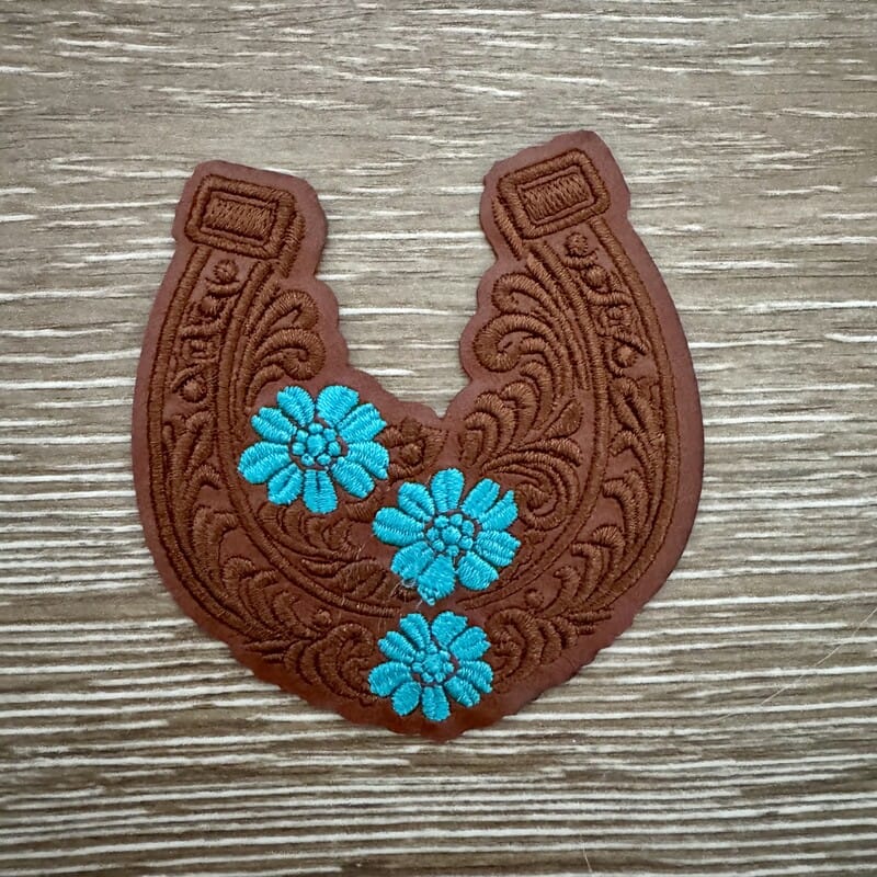 Tooled leather look horseshoe iron-on patch in brown with turquoise daisy flowers