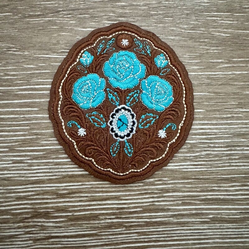 Turquoise roses tooled leather style iron-on patch on brown western oval with scrollwork