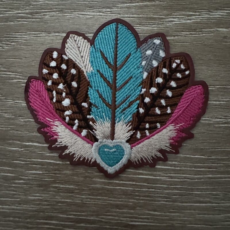Turquoise speckled feather fan embroidered iron-on patch with brown and hot pink feathers on a turquoise heart