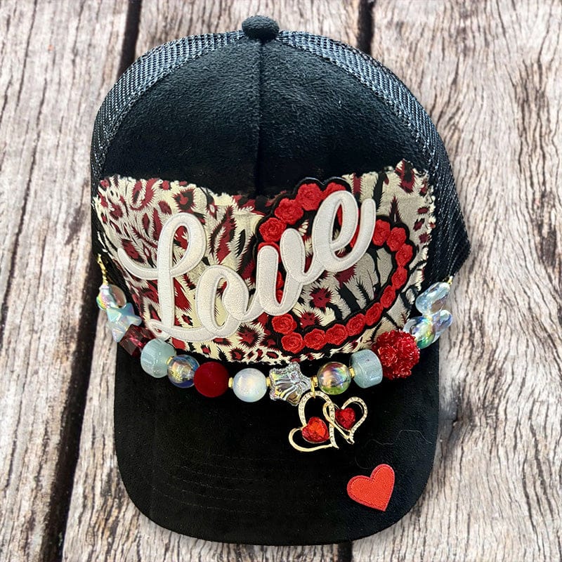 Black suede trucker hat with Love patch, red leopard tapestry and gold heart charm beaded chain by On A Whim Hats